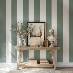 Modelo Della, papel pintado de rayas oliva y blanco lino, a escala maxi en pasillo o recibidor con consola de madera, decorada con un marco grande con una fotografía de un paisaje y otros elementos decorativos.