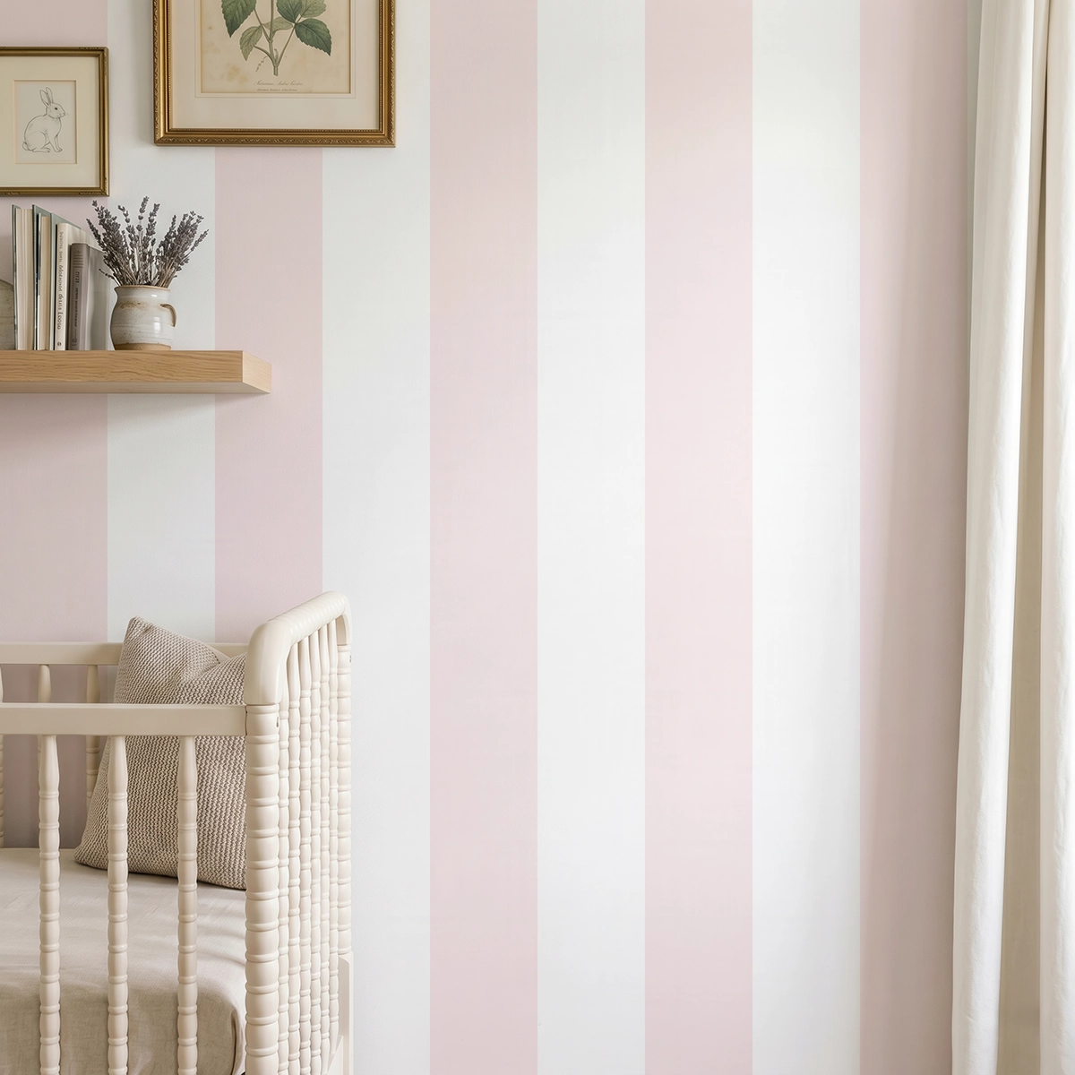 Modelo Della, papel pintado de rayas rosa nude y blanco, a escala maxi en dormitorio infantil con cuna de bebé y pared decorada con una pequeña estantería con elementos decorativos.