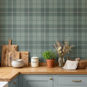 Modelo Oscar, papel pintado tartán verde bosque y gris, a escala mediana en cocina rústica con encimera de madera, sobre la cual aparecen utensilios de cocina y un tarro de cristal con flores silvestres..