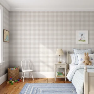 Modelo Oscar, papel pintado tartán beige, a escala pequeña en habitación infantil elegante con muebles de madera de color crema, con juegos apilados en una cesta de mimbre.