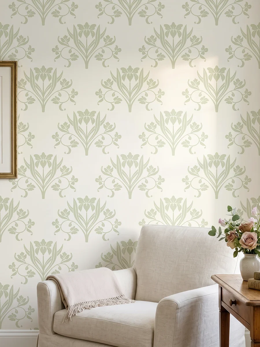 Liria, papel pintado floral verde salvia y marfil, a escala grande en salón luminoso con butaca, decorado con cuadros y elementos vegetales.