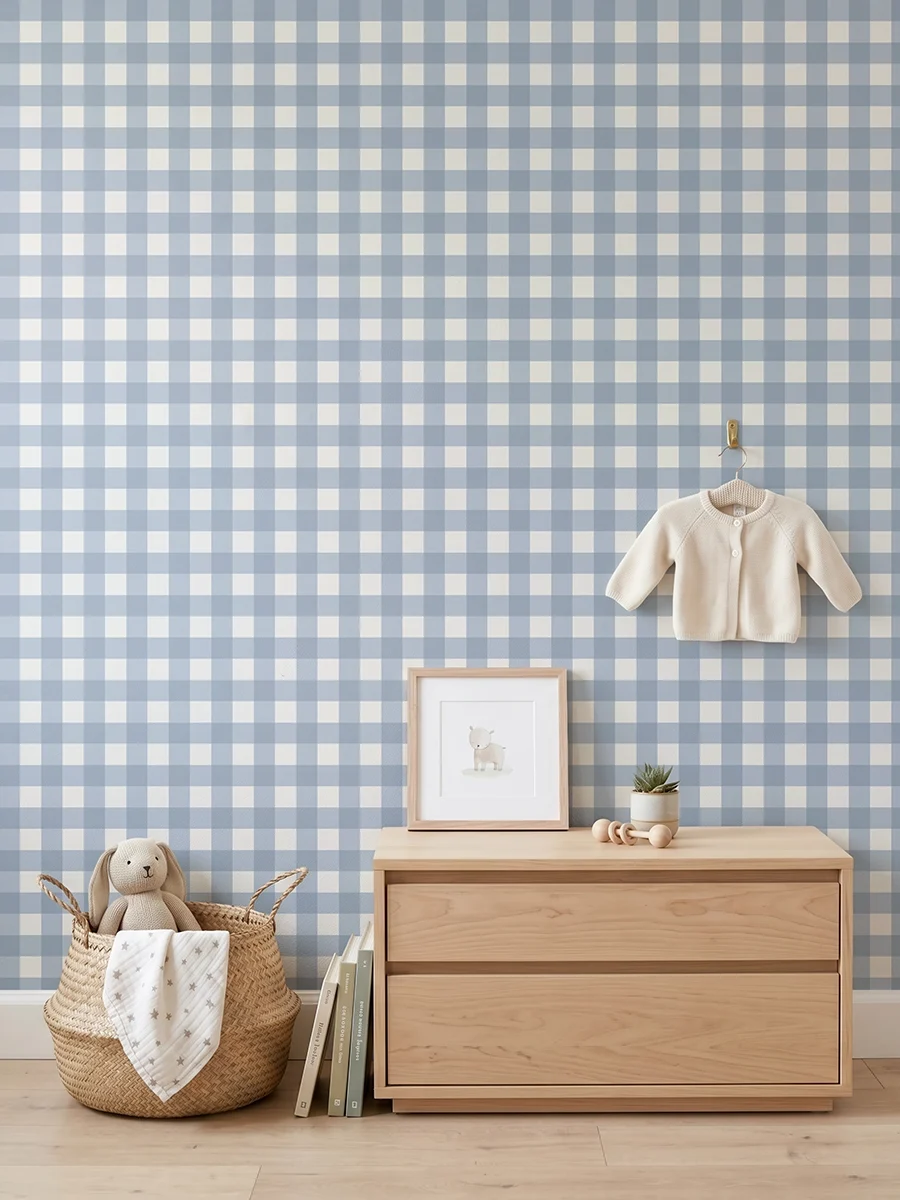 Anna, papel pintado Vichy azul empolvado y blanco lino, a escala pequeña en habitación infantil con cómoda, elementos decorativos y mobiliario de estilo natural.