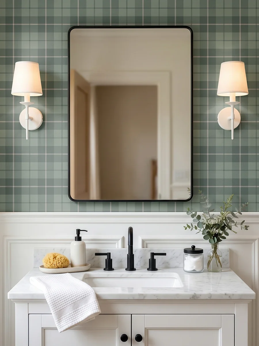 Modelo Oscar, papel pintado tartán verde bosque y gris, a escala pequeña en baño clásico con mueble de lavabo y espejo cuadrado a cuyos lados se sitúan unos apliques de luz clásicos y elegantes..