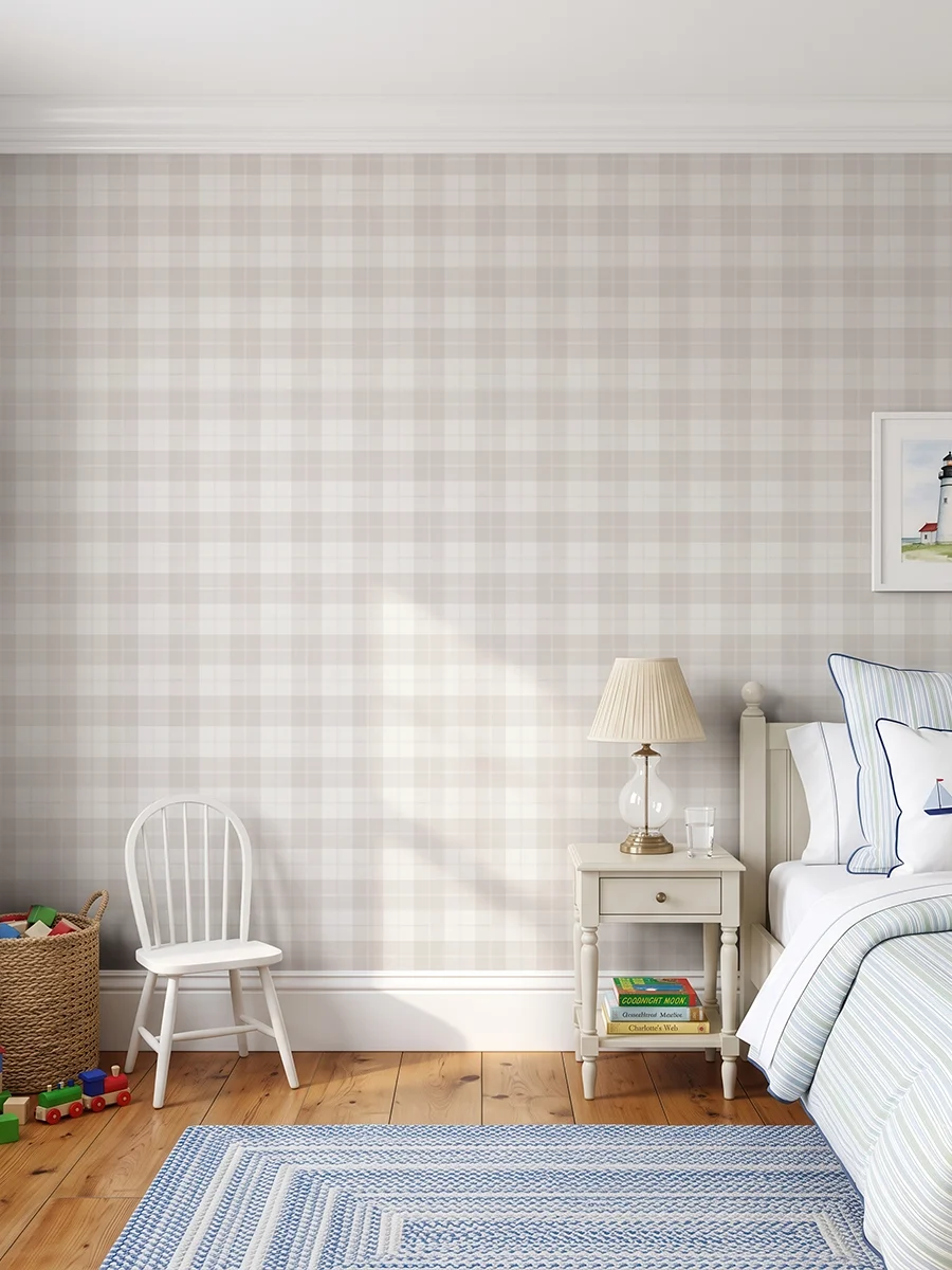 Modelo Oscar, papel pintado tartán beige, a escala pequeña en habitación infantil elegante con muebles de madera de color crema, con juegos apilados en una cesta de mimbre.