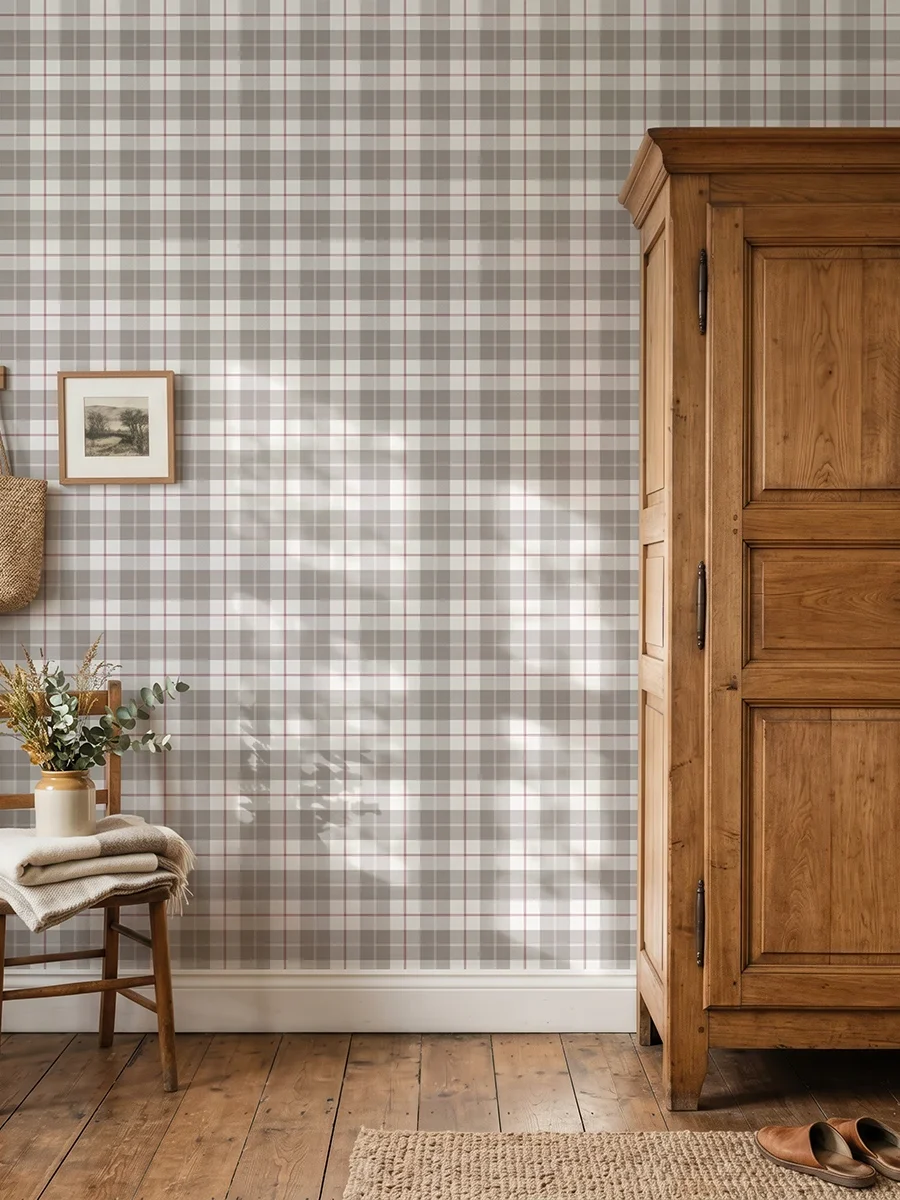 Modelo Oscar, papel pintado tartán taupé y berenjena, a escala pequeña en pared en habitación de estilo rústico con armario y silla de madera y una percha en la pared de la que cuelgan unas prendas.